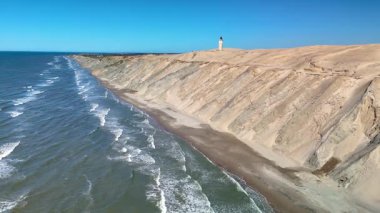 Danimarka 'nın Jutland kentindeki Rubjerg Knude Fyr Deniz Feneri' nin nefes kesici kıyı şeridini keşfedin. Altın kumlar ve dalgalar, güneşlenmek, araba sürmek ve sakin bir sahil inzivasına çekilmek için mükemmel.