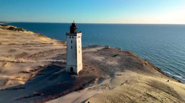 Bu büyüleyici manzara, tarihi deniz fenerinin, sonsuz kumların ve Jutland, Danimarka 'daki sakin Kuzey Denizi' nin zemininde gururla durduğunu gösteriyor.