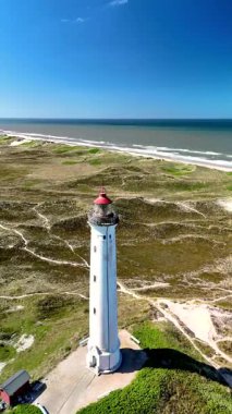Lyngvig Deniz Feneri Hvide Sandein Jutland, Danimarka. Yükselen kum tepeleri, tarihi bir deniz feneri ve geniş okyanus manzaraları rahatlama ve macera için mükemmel sakin bir atmosfer yaratır..