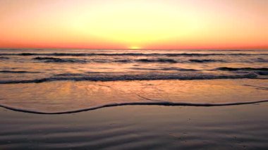 Günbatımında Danimarka 'daki Romo Lakolk plajının dingin güzelliğini görün. Altın renkler yumuşak dalgaları yansıtarak rahatlatıcı bir atmosfer yaratıyor..