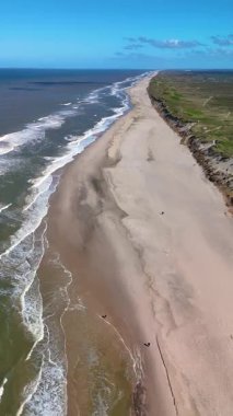 Danimarka 'nın Jutland kentindeki Lakolk Sahili' nin huzur dolu güzelliğini keşfedin. Bu manzaralı kıyı şeridi sakin sürüş ve dinlendirici yürüyüşler için mükemmel, yumuşak dalgalar ve el değmemiş doğa tarafından çerçevelenmiş..