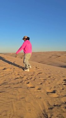 Yalnız bir figür, Danimarka 'nın Rubjerg Knude Jutland kentindeki geniş kum tepelerinde geziniyor. Altın kumlar ve canlı gökyüzü sakin bir atmosfer yaratır.
