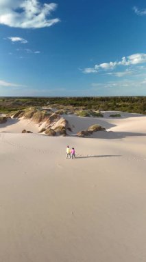 İki kişi, Danimarka 'nın Rabjerg Mile Jutland kentindeki sakin kum tepeleri boyunca huzurlu bir yürüyüş yapıyor. Geniş kıyı bereketli kum tepeleri ve parlak mavi gökyüzü tarafından çerçevelenmiştir.,