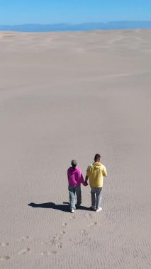 Danimarka 'nın Jutland kentindeki kumlu kumullarda el ele dolaşarak, açık mavi gökyüzünün altındaki altın manzaranın güzelliğine daldılar. Rabjerg Mil kum tepeleri