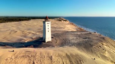 Danimarka 'nın Jutland şehrinde günbatımında Rubjerg Knude Fyr Deniz Feneri' nin çarpıcı kumullarında dolaşın. Huzurlu manzarada Kuzey Denizi 'ne bakan tarihi bir deniz feneri bulunur.