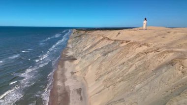 Danimarka 'nın Jutland kentindeki Rubjerg Knude Fyr Deniz Feneri' nin dingin güzelliğini keşfedin. Orada altın kumlar berrak mavi bir gökyüzünün altında sakin denizle buluşur. Rahatlamak ve macera yaşamak için mükemmel bir yer..