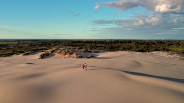 Çift, Danimarka, Jutland 'ın geniş kumullarında el ele yürür. Hareketli tepeler, canlı yeşillikler, Rabjerg Mil kum tepeleri...