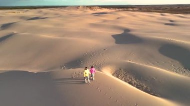Danimarka, Jutland 'ın yumuşak, dalgalı kum tepelerini aşan iki birey, huzurlu bir öğleden sonra boyunca geniş kumlu manzaralarla çevrili. Rabjerg Mil kum tepeleri
