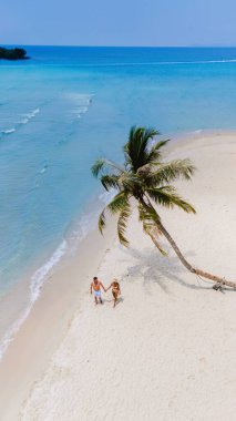Turkuvaz suları ve sallanan bir palmiye ağacıyla çevrili el ele el ele el ele el ele gezen el değmemiş beyaz bir kumsal. Koh Kood Tayland adasında tatilde olan çift.