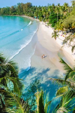 Dalgalar, bereketli palmiye ağaçlarıyla çevrili el değmemiş kumlu bir plaja nazikçe çarpar. Çiftler kıyı şeridinde yürüyüp Koh Kood Tayland 'ın güneşli ve berrak turkuaz sularının tadını çıkarıyorlar.