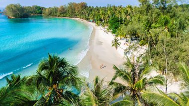 Parlak turkuaz sular yumuşak kumlu kıyılarla buluşurken palmiye ağaçları hafif esintide sallanıyor. Güneş banyosu yapanlar, Koh Kood Tayland 'da dinlenmek için mükemmel sakin bir atmosfer yaratarak boş zamanların tadını çıkarırlar.
