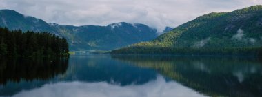 Sakin sular Norveç 'in yemyeşil dağlarını yansıtıyor. Sakin göl çevresindeki doğayı yansıtıyor. Araksfjorden' in vahşi doğasına hoş bir kaçış sunuyor.