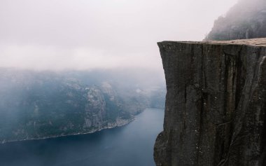 Preikestolen Norveç 'te sisle kaplı sakin bir mavi fiyordun üzerinde dramatik bir uçurum yükseliyor. Bu büyüleyici manzara Norveç 'in doğal güzelliğini ve büyüleyici coğrafyasını yansıtıyor.
