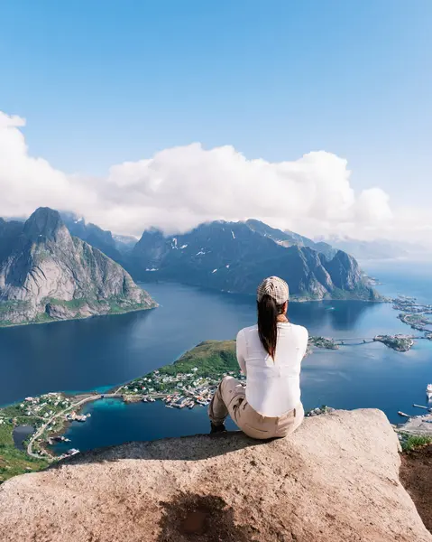 Bir gezgin, dramatik dağlar ve sakin sularla çevrili Lofoten Adaları 'na bakan kayalık bir levrekten çarpıcı manzaranın keyfini çıkarır..