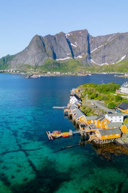 Renkli evler, Lofoten Norveç 'teki görkemli dağlarla çevrili kayalık bir köyün kayalık kıyısında yer alır. Huzurlu sular canlı renkleri yansıtır, keşif ve macerayı davet eder..
