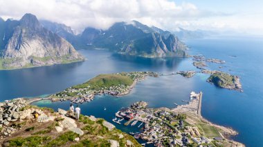 Norveç 'in Lofoten kentindeki canlı kıyı köyünü çevreleyen dağlardır. Kristal berrak sular, ziyaretçilerin büyüleyici manzaraya hayran kalmaları nedeniyle yemyeşil suları yansıtıyor. Reinebringen dağı Lofoten Norveç