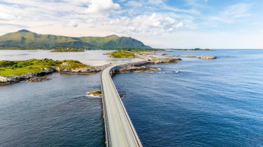 Parıldayan sular üzerinde uzanan güzel bir kıyı yolu adaları birbirine bağlıyor ve Norveç 'in yemyeşil dağlarını ve berrak mavi gökyüzünü büyüleyici bir şekilde gösteriyor. Atlantik Okyanusu Yolu, Norveç