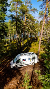Yüksek çam ağaçlarının arasına kurulmuş bir karavan, Norveç 'in vahşi doğasının huzurlu güzelliğinin tadını çıkarıyor..