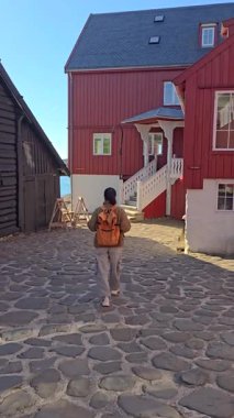 Bir gezgin, geleneksel renkli evlerin gururla durduğu Torshavn 'un kaldırım taşı caddelerinde yürüyor. Güneş, bu sakin sahil kasabasının güzelliğini artırmak için ılık bir ışık saçıyor..