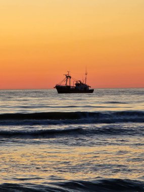 Sakin bir günbatımı gökyüzünde ılık renkler bırakır ve nazik dalgaları yansıtır. Danimarka kıyı yaşamının özünü somutlaştıran bir balıkçı teknesi huzur içinde denizde sürükleniyor..