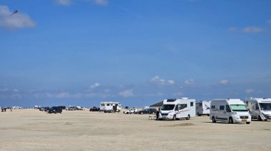 Romo Danimarka 12 Mayıs 2025 'te kampçılar ve araçlar, ziyaretçilerin açık mavi bir gökyüzünün altında dinlendiği geniş kumlu bir plaj hattı oluşturdu. Uzaktaki uçurtmalar uçarken, burası deniz kenarında mükemmel bir gün sunuyor..