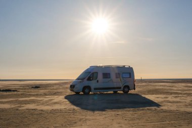 Lakolk Strand, Romo, 11 Mayıs 2025, Danimarka, sakin bir plajda dinlenen bir karavan, sıcak güneş ışığı altında yıkanır. Uçsuz bucaksız kumlu kıyı şeridi sonsuz genişliğe ulaşıyor ve sakin bir atmosfer yaratıyor.