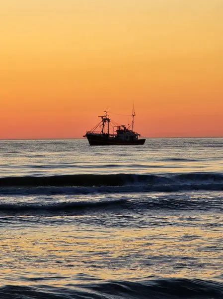 Sakin bir günbatımı gökyüzünde ılık renkler bırakır ve nazik dalgaları yansıtır. Danimarka kıyı yaşamının özünü somutlaştıran bir balıkçı teknesi huzur içinde denizde sürükleniyor..