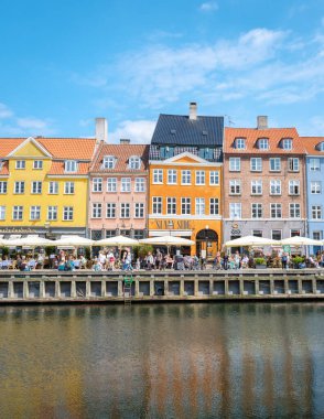 Nyhavn, Kopenhag, Danimarka, 12 Temmuz 204: liman binaları, yerel halkın ve turistlerin açık hava yemeklerini sevdiği ve sakin bir şekilde yürüdükleri kanalın sakin sularına yansıyor. 