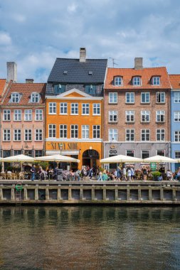 Nyhavn, Kopenhag, Danimarka 12 Temmuz 204, Bustling rıhtım kafeleri ziyaretçilerini resimli bir alana çağırıyor. Kanal boyunca renkli binalar var.