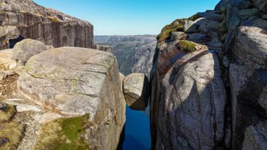Kjeragbolten 'in nefes kesici güzelliğini keşfedin. Norveç' teki Lysefjord 'un üzerindeki iki uçurumun arasına tünemiş devasa bir kaya parçası. Bu ikonik simge çarpıcı manzaralar ve heyecan verici maceralar sunar..
