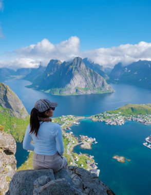Bir yürüyüşçü, Norveç 'teki bir dağın tepesinde sersemletici fiyortlara ve hareketli köy yaşamına tepeden bakan huzurlu bir anın tadını çıkarır. Reinebringen Lofoten Norveç