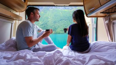 Bir çift rahat bir karavanda dinleniyor, kahveyi yudumlarken nefes kesici Norveç manzarası seyrediyor. Sakin sular ve tepeler mükemmel bir sabah ortamı yaratır..