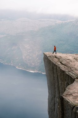 Preikestolen Norveç 'te sakin fiyortlara ve sisli dağlara tepeden bakan dramatik bir uçurumun kenarında yalnız bir yürüyüşçü duruyor. Doğanın güzelliğini ve keşfin heyecanını yakaladığı an..