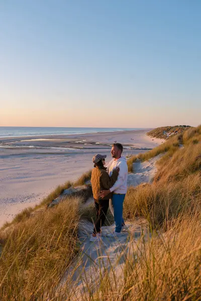 Bir çift uzun otlarla çevrili kumlu bir kumulda birbirine yakın duruyor. Blokhus Strand Sahili Danimarka