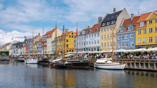 Nyhavn, Kopenhag, Danimarka, 12 Temmuz 204: Bu pitoresk liman bölgesi, tarihi binaların canlı cephelerini, limanı çevreleyen büyüleyici tekneleri ve canlı açık havada oturma yerlerini sergiliyor.