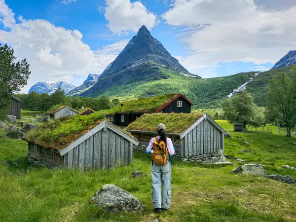 Bir gezgin Norveç 'in bereketli yeşil manzarasını keşfeder, manzaralı dağlar ve çimen çatılı geleneksel ahşap kulübelerle çevrilidir. Doğa ve kültürün mükemmel bir karışımı..