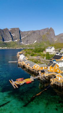 Kaleler üzerindeki renkli ahşap kulübeler görkemli dağlarla çevrili Norveç fiyortlarının sakin suları boyunca uzanır. Mükemmel bir yaz günü Lofoten Adaları 'nın güzelliğini vurgular..
