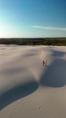 İki arkadaş Jutlands 'in yumuşak, güneşle öpülmüş kumlarında geziniyor büyüleyici kıyı şeridinde. Geniş manzaralarda yuvarlanan kum tepecikleri Rabjerg Mile ve berrak mavi gökyüzü, barışçıl bir geri çekilme için mükemmel.