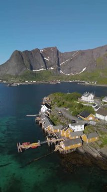 Lofoten Norveç 'te kıyı köyünün cazibesini deneyin, kıyı şeridi boyunca görkemli dağlarla çevrili renkli ahşap evler..