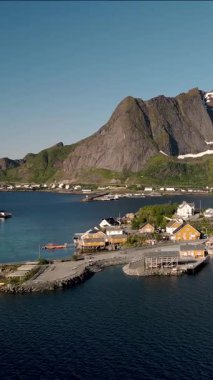 Norveç 'te renkli evlerin yüksek dağlara karşı yuva yaptığı büyüleyici bir kıyı köyü keşfedin. Sakin sular Sakrisoy, Moskenes, Lofoten adalarının canlı manzarasını yansıtır. Norveç.