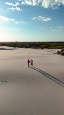 Neşeli bir çift, Danimarka 'nın Rabjerg Mile Jutland kentindeki sakin kum tepeleri boyunca el ele yürür. Geniş kıyı şeridi ve canlı gökyüzü manzaralı bir ortam yaratır. 
