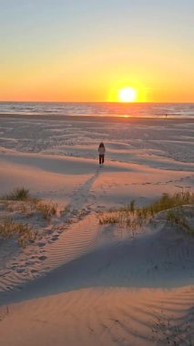 Jutland 'deki Lakolk sahillerinde huzurlu bir günbatımı yürüyüşü doğanın huzur dolu özünü yakalar. Kumda ayak izleri parlak bir ufka doğru gidiyor..