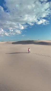 Danimarka, Rabjerg Mile Jutland 'ın büyüleyici kumlu kumullarında berrak mavi bir gökyüzünün altında, kabarık bulutlarla el ele yürüyen iki birey. Barışçıl manzara keşfe ve maceraya davetiye çıkarır..