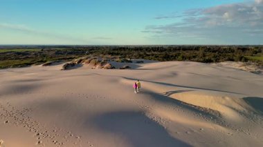 Bir çift gün batımında Jutlands 'in yumuşak, altın kumlarında el ele yürür. Rabjerg Mil kum tepeleri