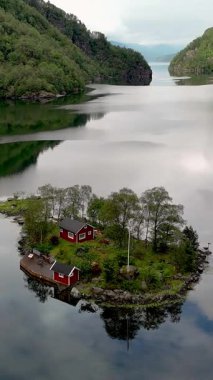Norveç, Lovrafjorden, beathing hava manzaralı sakin sular ve yemyeşil fiyortlarla çevrili küçük bir adada yuvalanmış büyüleyici kırmızı bir ev sergileniyor..