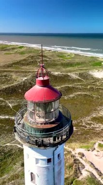 Danimarka 'nın Jutland kentindeki Lyngvig Deniz Feneri Hvide Sande' nin çarpıcı kıyı manzarasını araştırın. Görkemli deniz feneri kumullara ve parlayan dalgalara bakıyor.