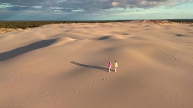 Romantik bir çift, Danimarka 'nın Jutland kentinin geniş kum tepelerinde rahatça dolaşarak geride yumuşak ayak izleri bırakır. Rabjerg Mil kum tepeleri