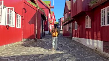 Torshavn 'un canlı kırmızı binalarında gezinen ziyaretçiler, Faroe Adaları' nın bu tarihi başkentinde güneşli bir günün tadını çıkararak yerel kültürün ve çarpıcı mimarinin özünü yakalıyorlar..