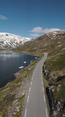 Fiyordu saran dolambaçlı bir yol ile Norveç 'in çarpıcı güzelliğini tecrübe edin. Karla kaplı zirveler sakin suları yansıtıyor, görkemli doğayı yansıtıyor..