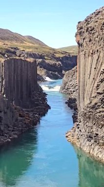 İzlanda 'nın nefes kesici güzelliğini keşfedin. Sakin bir nehir boyunca uzanan eşsiz bazalt kayalıkları keşfedin. Sakin turkuaz su, dayanıklı taş Studlagil Kanyonu İzlanda ile mükemmel bir zıtlık yaratır.